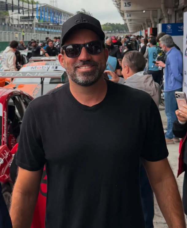 Alex Veiga de camiseta e boné pretos em um evento automotivo